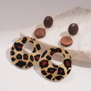 Détail de boucles d'oreilles léopard en résine et perles en bois sur une pierre blanche