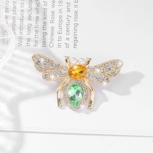 Luxury bee brooch with sparkling crystals and colorful gemstones on a vintage book