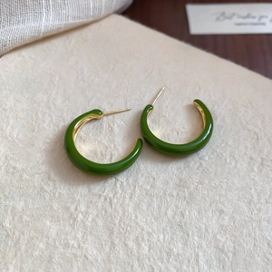 Detailed view of dark green enamel C-shaped hoop earrings with gold metal finish