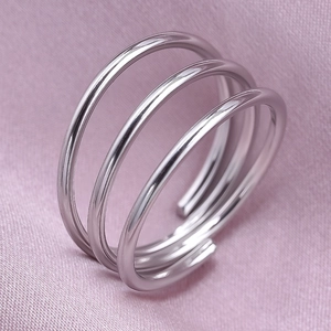 Macro shot of silver triple-layered spiral ring on soft pink fabric background