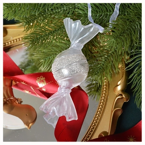 Dettaglio di un ornamento natalizio a forma di caramella trasparente con glitter argento