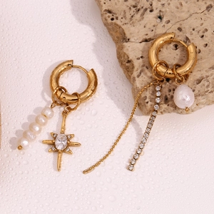 Detail of asymmetric pearl earrings with zircon stars and sparkling rhinestone tassels