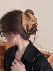 Détail d'une élégante pince à cheveux en satin marron avec bouton doré sur modèle