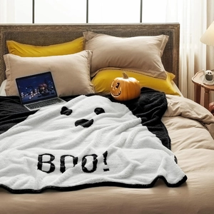 Soft Halloween ghost blanket with BOO! print displayed on a cozy bed with pumpkins