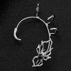 Gothic silver spider ear cuff with black gemstone on a dark textured background