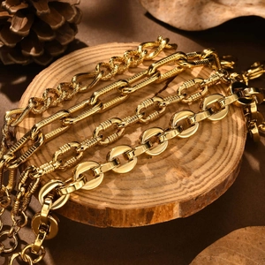 Set of four gold stainless steel link bracelets with oval embossed textures on wood base
