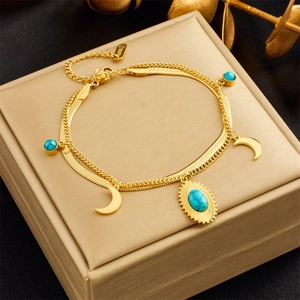 Detailed close-up of gold double-layer bracelet with moon pendant and blue stone charms