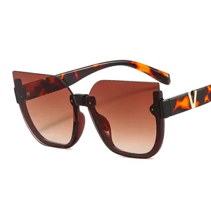 Stylish cat-eye sunglasses in tortoiseshell frame with golden V decoration and brown gradient lenses