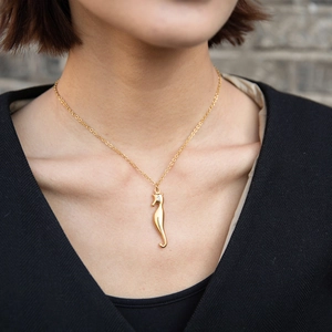 Detail shot of a gold seahorse pendant with a tiny sparkling stone on an O-chain link