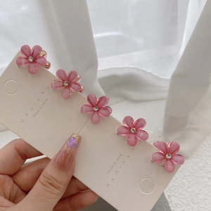 Detail of five pink flower hair clips with rhinestones on a white card display