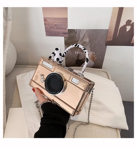 Detail of camera-shaped gold mirror bag with polka dot scarf handle and chain