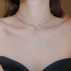 Detail of a gold lace pendant necklace with sparkling cubic zirconia on a female model