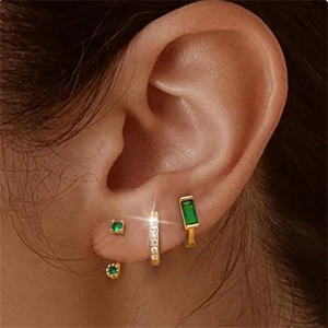 Close-up of gold s925 silver earrings set with green emeralds and white zircons