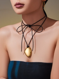 Detail of 18k gold heart pebble pendant on multi-strand black cord necklace worn by model