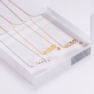 Detailed view of LOVE pendant necklaces in gold, silver, and rose gold with pavé crystals