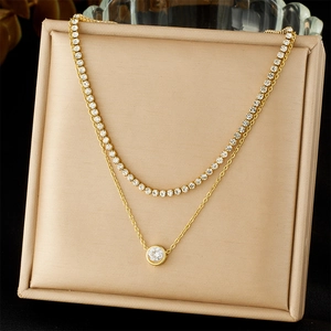 Detail of layered gold double-chain necklace with sparkling zircon and round pendant