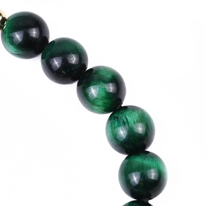 Macro shot of green tiger eye beads showing natural cat-eye texture and polished finish
