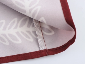 Detailed close-up of leaf pattern fabric with burgundy piping and high-quality stitching