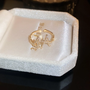 Macro shot of gold double A-letter crisscross ring with zircons in a white velvet box
