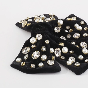 Dettaglio del fermaglio in velluto nero con strass scintillanti e perle incastonate