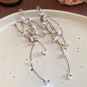 Detail shot of bohemian tassel earrings with shells and woven ropes on ceramic plate