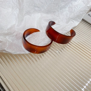 Macro shot of retro amber leopard print resin C-shaped hoop earrings with silver pins