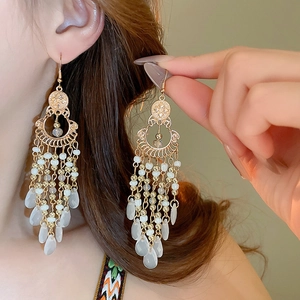 Bohemian gold crescent moon earrings with intricate cutout design and white beaded tassels