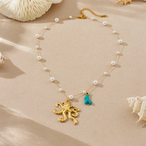 Collana minimalista con polpo in acciaio inossidabile, perle e corallo su sfondo sabbia