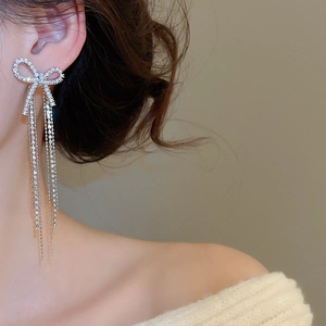 Detail of silver bow tassel earrings featuring micro-pave cubic zirconia on model