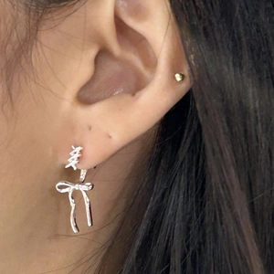 Close-up of S925 silver bow stud earring with twisted rope texture on a model's ear
