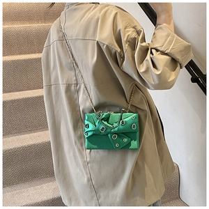 Green satin evening bag with rhinestone buckle and gold chain shown on a model
