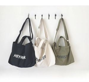Detailed view of canvas tote bags in black, cream and green with adjustable straps