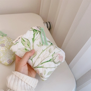 Detailed macro view of floral quilted cotton pouch featuring pink roses and green zipper cord