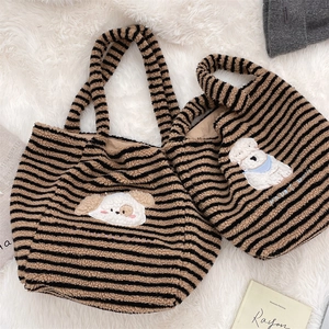 Detail of striped plush tote bags with cute cartoon dog embroidery on soft carpet