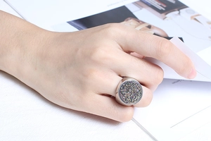 Close-up of a large round druzy crystal ring on finger with brushed steel texture