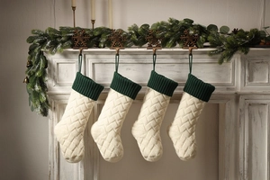 Close-up of cable knit Christmas stockings with green cuffs on a festive fireplace