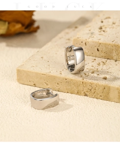 Detail of square S925 sterling silver hoop earrings on natural stone with soft lighting