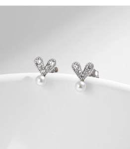 Macro view of S925 silver heart stud earrings with sparkling crystals and white pearls