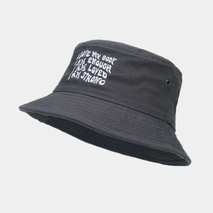 Detail of embroidered inspirational quotes and metal eyelets on a black bucket hat