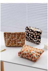 Close-up of floral corduroy cosmetic bags with zipper and branded label in three colors