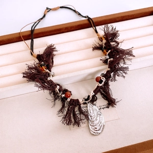 Detail of woven boho necklace with dark brown tassels and silver seashell pendant charm