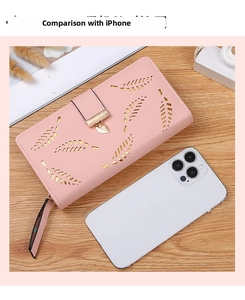 Size comparison of light pink leaf hollow wallet next to an iPhone on wooden desk