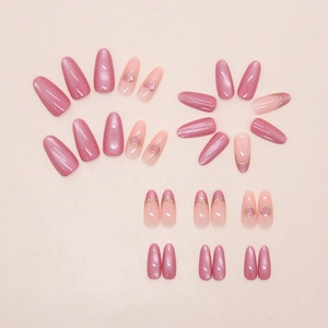Detail of pink cat-eye press-on nails with 3D heart motifs and golden French lines
