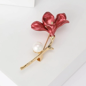 Macro shot of red trumpet flower brooch with golden stem and white faux pearl detail