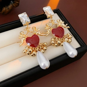 Detailed macro shot of vintage gold earrings with red heart, zircon, and drop pearls