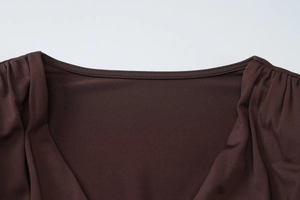 Detailed close-up of a deep brown knit dress neckline with premium stitching and finish