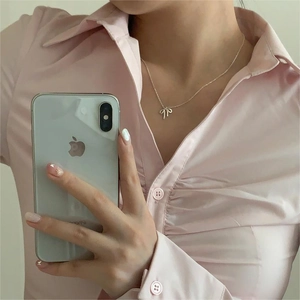 Mirror selfie showing the elegant silver bow necklace on a pink pleated shirt