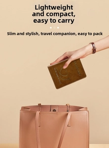 Brown PU leather passport holder with gold heart logo being placed in a pink handbag