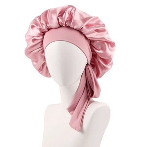 Detailed view of pink satin sleep cap with long ties and ruffled edges on model