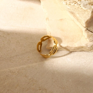 Dettaglio dell'anello a catena dorato regolabile su uno sfondo in pietra materica